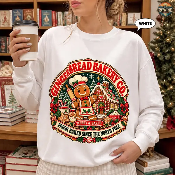 Model wearing a White Christmas crewneck sweatshirt with a colorful Gingerbread Bakery Co. print featuring a cookie baker, gingerbread house, holiday sweets and holly.